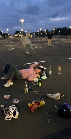 a man laying on the ground with his head down in an empty parking lot at night