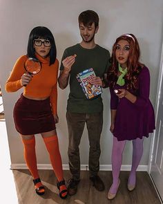 three people dressed up in halloween costumes standing next to each other and holding candy bars