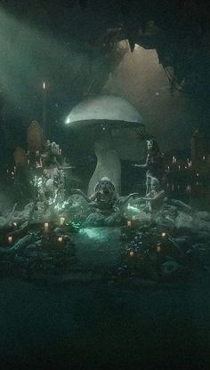 a group of people standing in front of a mushroom shaped structure with candles on the ground