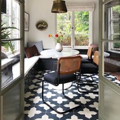 a dining room with black and white tile flooring, chairs and table in the corner