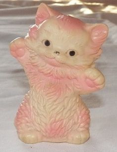 a small ceramic cat figurine sitting on its hind legs with one paw in the air