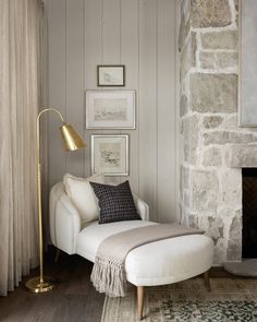 a white chair sitting next to a fire place in a living room under a window