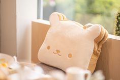 a teddy bear pillow sitting on top of a wooden table next to a window sill