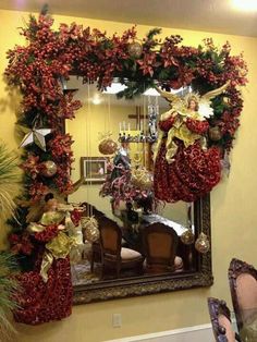 a christmas wreath is hanging on the wall in front of a mirror with ornaments and decorations around it