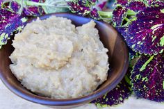 a bowl filled with mashed potatoes next to purple flowers