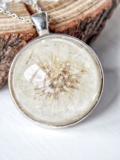 a dandelion necklace sitting on top of a piece of wood