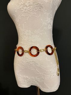 a white mannequin torso with a gold chain and tortoise shell bracelet