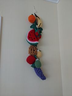 a crocheted fruit and vegetable decoration hanging on the wall