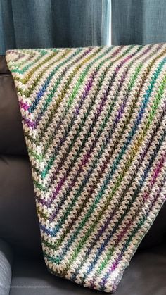 a crocheted blanket sitting on top of a couch next to a black leather chair