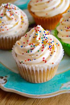 cupcakes with white frosting and sprinkles on a plate