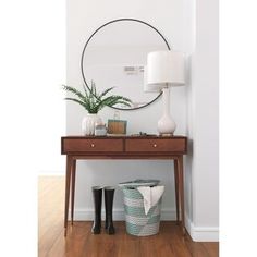 a wooden table topped with a mirror next to a lamp and potted plant on top of it