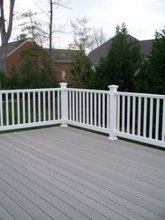 a white deck with railings and trees in the background