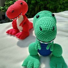 two crocheted stuffed animals sitting on top of a white surface next to each other