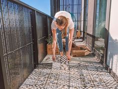 a woman bending over to pick up something from the ground on top of a tiled floor