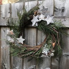 a wreath with silver stars hanging on a wooden fence