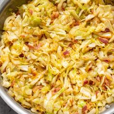 a bowl filled with cabbage and bacon on top of a table