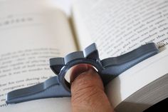 a person is holding an open book with a ring on it's thumb and reading the book