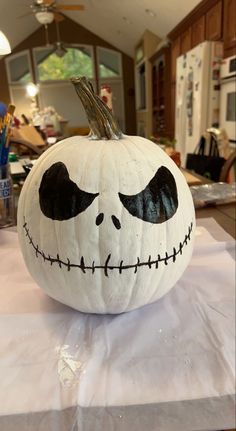 a pumpkin decorated with the face of jack skellingy on top of a table