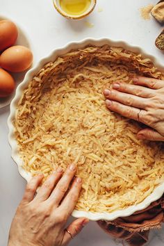 two hands on top of a pie crust in front of some eggs and other ingredients