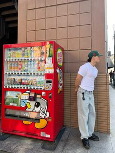 a man standing next to a vending machine on the side of a building,