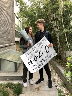 a man and woman standing next to each other holding a sign