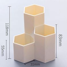 three white vases sitting on top of each other in front of a measuring line