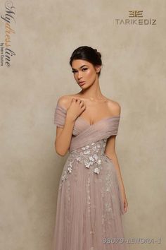 Capture hearts and imaginations with the ethereal beauty of the Tarik Ediz 98079. This A-Line Off the Shoulder Long Evening Dress is a dream come true for any special occasion. With its romantic V-Neck and mesmerizing pleating, it exudes an air of enchantment. Crafted from lightweight Chiffon and Tulle, this gown is a delicate masterpiece, adorned with beautiful flowers that add an extra touch of charm. The strapless style effortlessly flatters every figure, while the open back creates a graceful and sophisticated allure that is bound to leave a lasting impression. Slip into this timeless gown and let your elegance shine on your special night. #EtherealBeauty #RomanticElegance #EnchantingCharm Wedding Gown Simple Elegant, Wedding Gown Simple, Embroidery Tulle, Sleeves Embroidery, Tarik Ediz, Rosy Brown, Full Length Gowns, Embroidered Fabric, Tulle Fabric