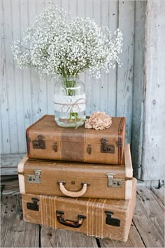 two suitcases stacked on top of each other with flowers in the vase next to them