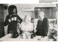 an old black and white photo of three people standing at a table with cups in front of them