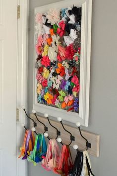 there is a coat rack with many scarves hanging from it's hooks on the wall