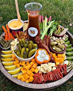 a platter filled with assorted vegetables and dips on the grass next to other foods