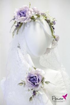 a white mannequin headpiece with purple flowers on it's face and veil