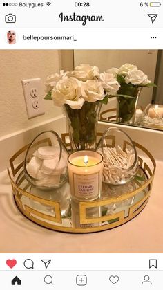 a candle and some flowers in a vase on a bathroom sink counter with a mirror above it