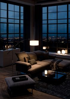 a living room filled with lots of furniture and large windows overlooking the city at night