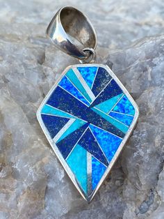 This beautifully well crafted Shield Pendant has been handmade by a Navajo Artisan. The Colors of the Pendant come from Lapis Lazuli, Turquoise and Blue Opal. The Pendant measures 2 1/8” long and 1 1/4” wide. These will vary in design due to natural stones. “Winds of Wisdom” (Lapis Lazuli, Turquoise and Blue Opal. The Navajo (Dine’) believe that the wind is a powerful source. The native tradition believes that at any moment, the blowing wind can inspire one with hope, resolve, and great wisdom. Artisan Blue Inlay Necklaces, Unique Blue Necklace With Inlay, Southwestern Blue Necklace With Inlay, Southwestern Blue Inlay Necklace, Southwestern Style Blue Inlay Necklace, Traditional Blue Inlay Necklaces, Traditional Blue Necklaces With Inlay, Traditional Blue Necklace With Inlay, Artisan Blue Jewelry With Inlay