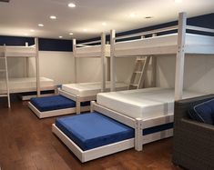 bunk beds are lined up in a room with blue and white sheets on the mattresses