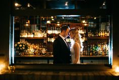 a bride and groom standing in front of a bar