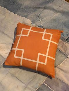 an orange and white pillow sitting on top of a bed