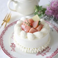 there is a small cake on the plate next to a teapot and fork with flowers in it