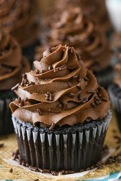 chocolate cupcakes with chocolate frosting and sprinkles on a table