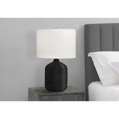 a black lamp sitting on top of a nightstand next to a bed