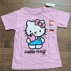 a pink hello kitty t - shirt sitting on top of a wooden floor