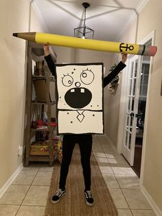 a person is holding up a sign with a pencil in the shape of a face