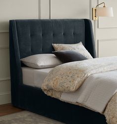 a bed with a blue headboard and two pillows on it's sides in a room