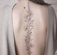 the back of a woman's shoulder with flowers and leaves on her left side