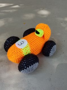 an orange knitted toy car sitting on the ground