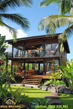 a house that is surrounded by palm trees and grass with stairs leading up to the upper level