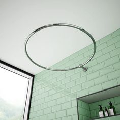 a bathroom with green tiled walls and a round light fixture hanging from the ceiling above it