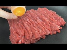 someone is pouring an egg on top of some raw meat in a frying pan