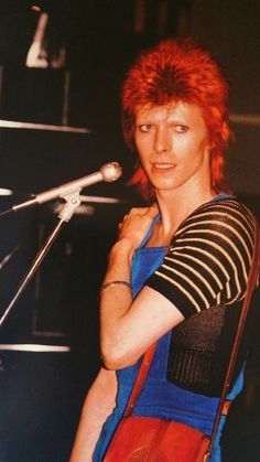 a woman with red hair is standing in front of a microphone and looking at the camera